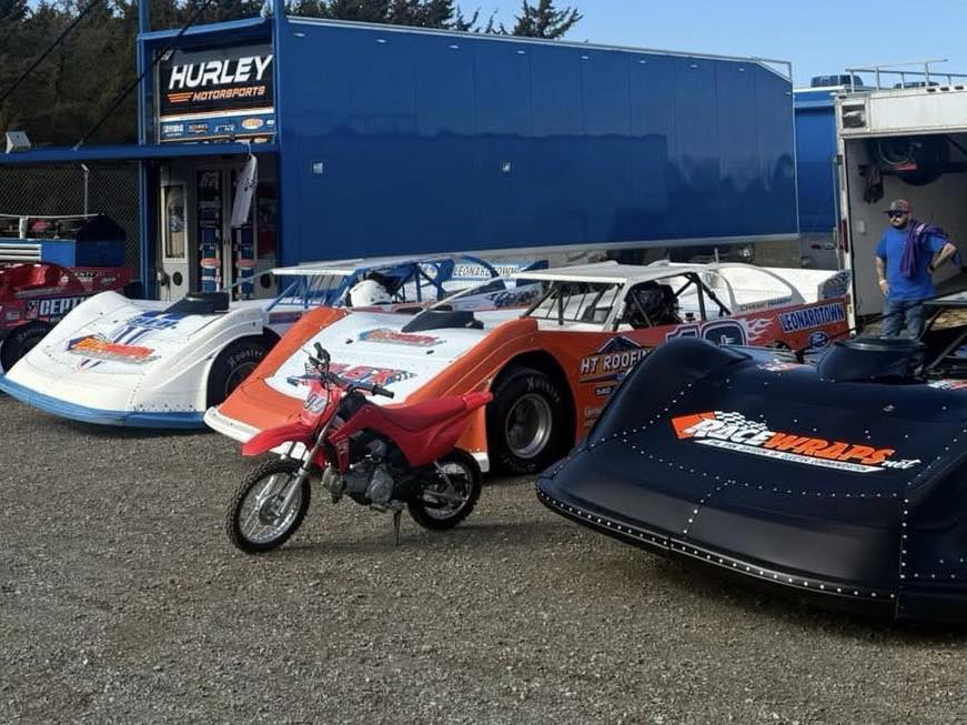 Multiple custom wrapped race cars at motorsports pit area
