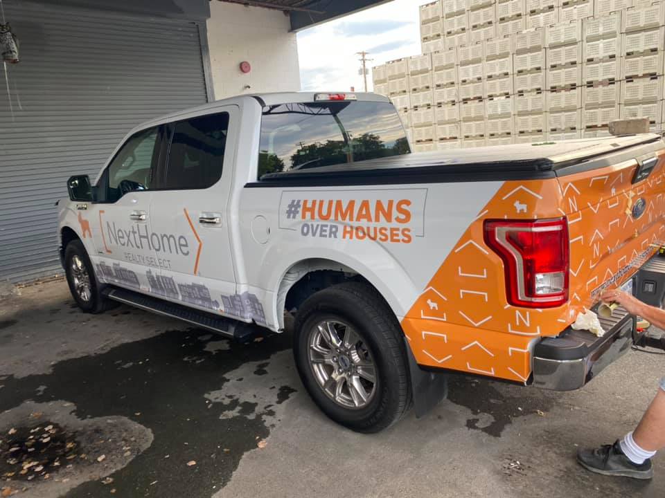 Rear view of NextHome Realty Select truck wrap with branded tailgate design